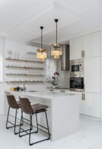 Sleek modern kitchen interior with white cabinets and elegant pendant lights.